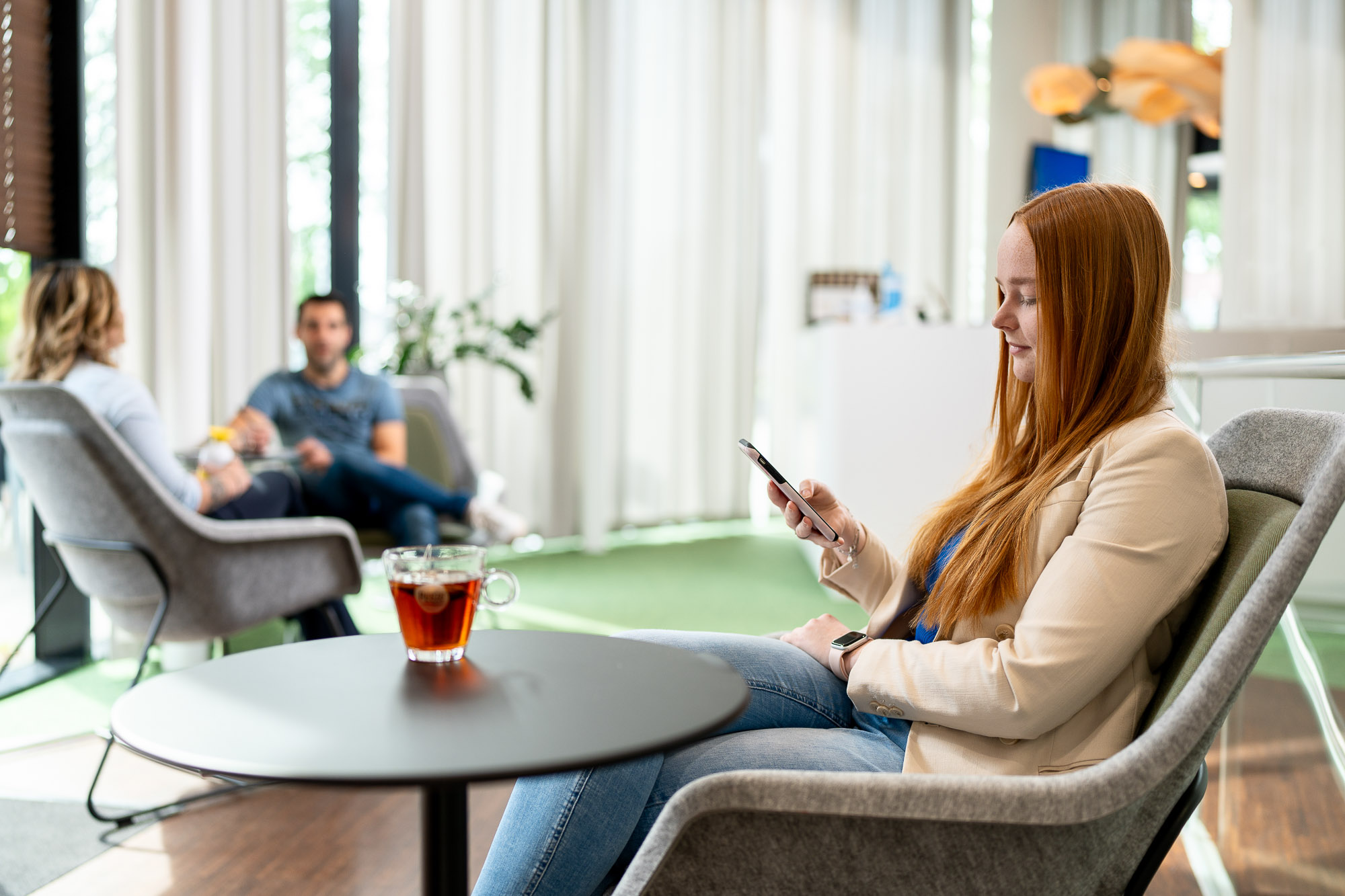 Vrouw op mobiele telefoon en een kop thee.