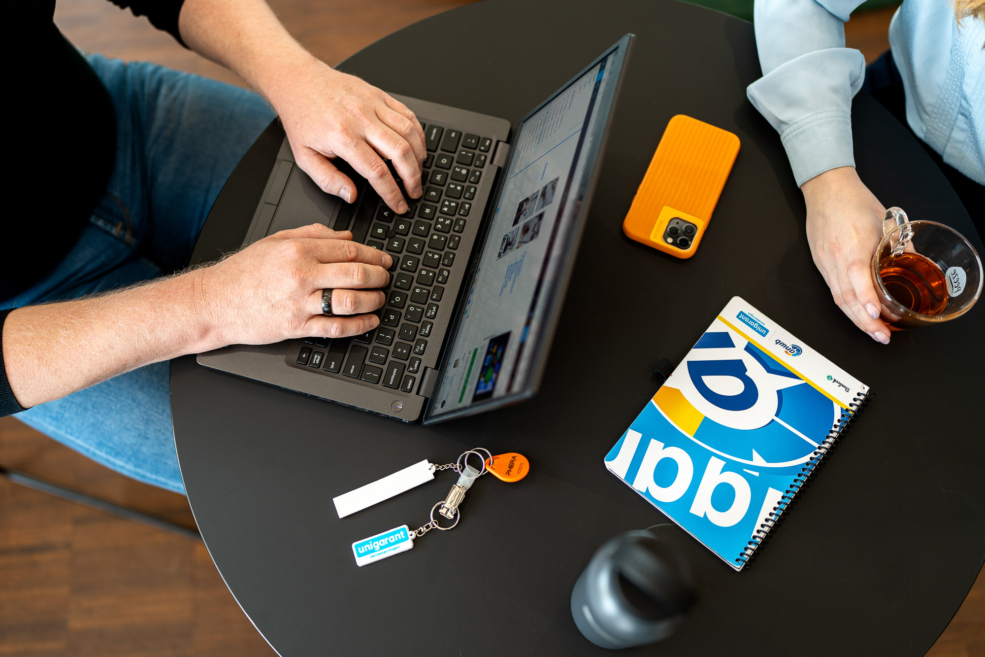 Collega's aan het werk van bovenaf met laptop, telefoon en notitieblok