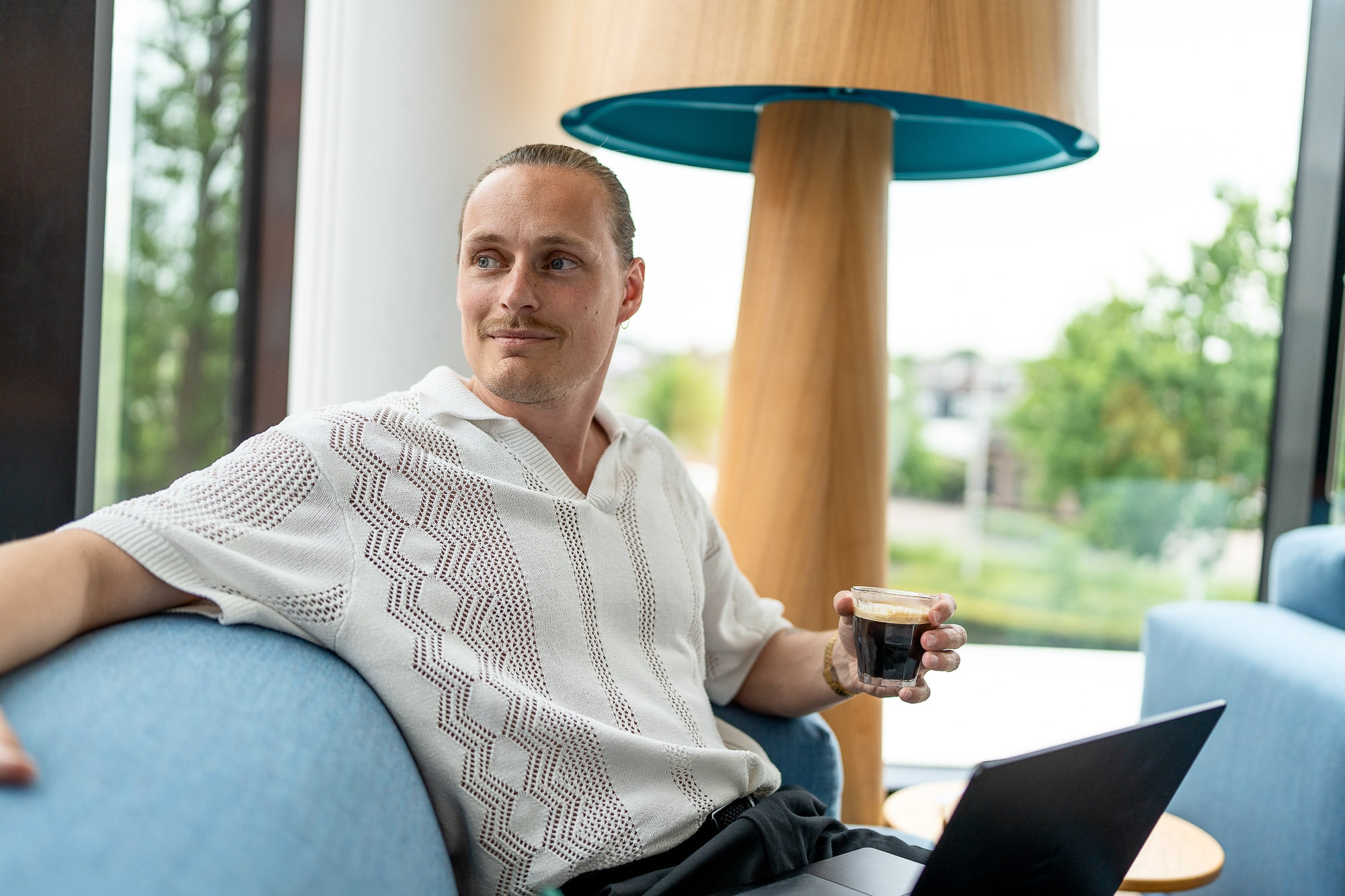 Medewerker van Unigarant drinkt koffie met laptop op schoot.