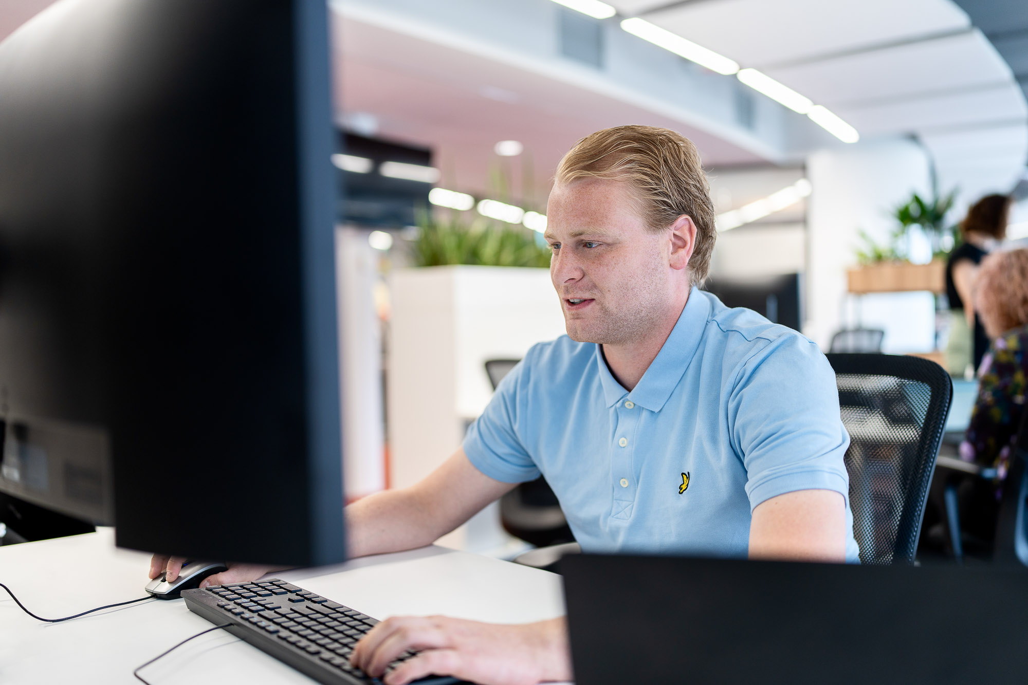 Collega aan het werk achter de computer. Wij gaan vertrouwelijk om met de gegevens van onze klanten.